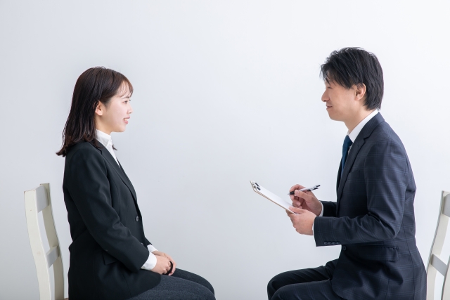 向かい合って面接を行うスーツ姿の女性と面接官の男性