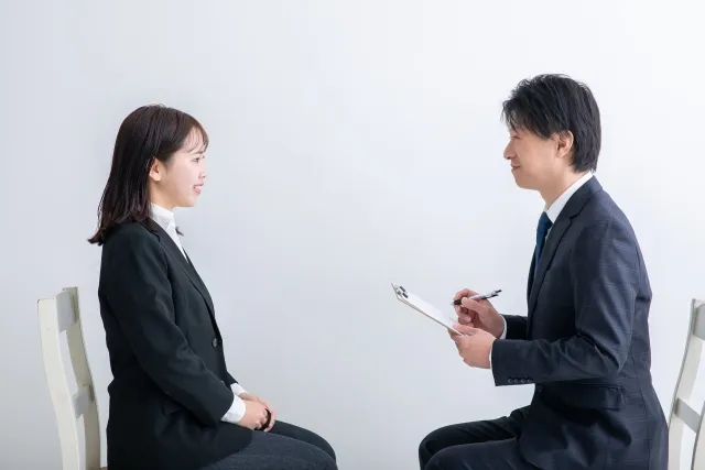 向かい合って面接を行うスーツ姿の女性と面接官の男性
