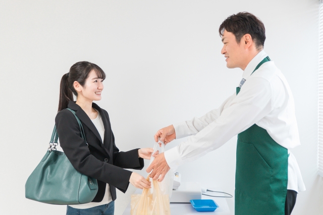 レジ対応を行う男性コンビニ店員と商品を受け取る女性客
