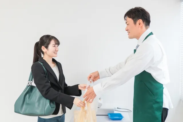 レジ対応を行う男性コンビニ店員と商品を受け取る女性客