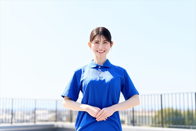 青空をバックにこちらに微笑む青い服を着た女性