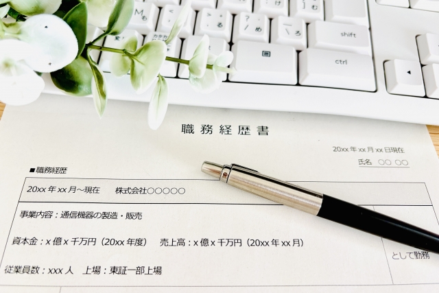 ペンが上に置かれた職務経歴書と白いPC