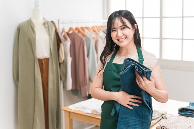 ジーンズをたたみながらこちらに微笑む女性店員