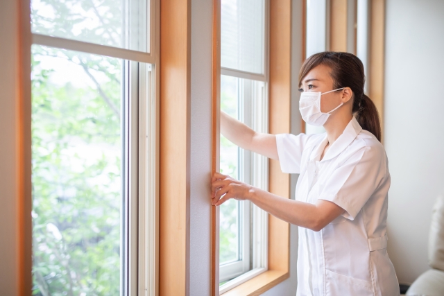 窓を開けて換気を行うナースの女性