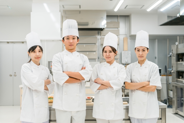 厨房に並んで立つ男女4人のキッチンスタッフ