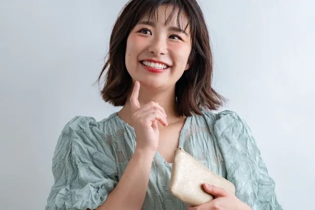金色の財布を手に微笑みながら何かを考える女性