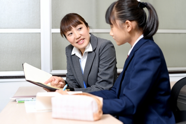 女子生徒に一対一で勉強を教える女性塾講師