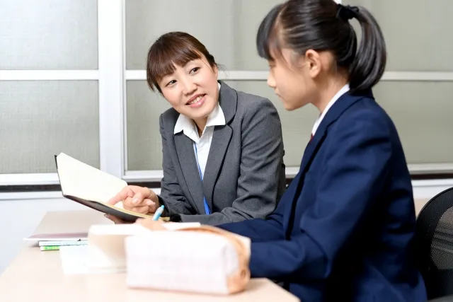 女子生徒に一対一で勉強を教える女性塾講師