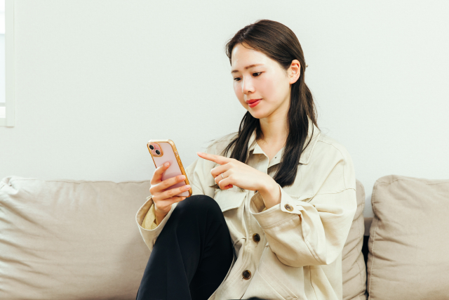スマホを見ながらソファーに腰掛ける女性