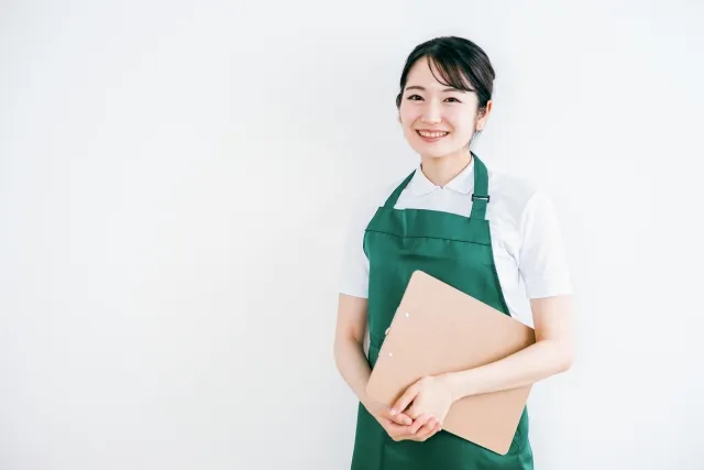 バインダーを手に微笑むエプロン姿の女性店員