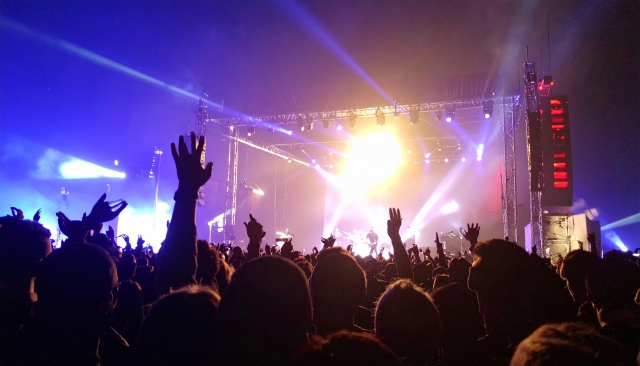 満員のライブ会場で盛り上がっている観客と舞台上のアーティストのイメージ