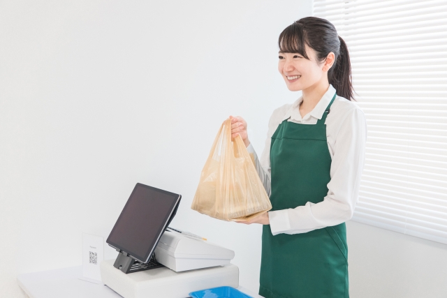 お客様に商品を手渡すレジ対応中の女性スタッフ