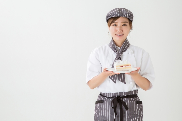 ショートケーキをもってこちらに微笑む女性スタッフ