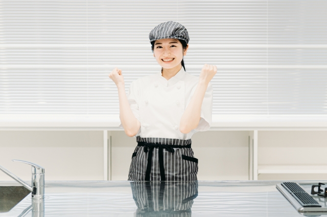 両手でガッツポーズをしながらこちらに笑顔を向ける女性調理スタッフ
