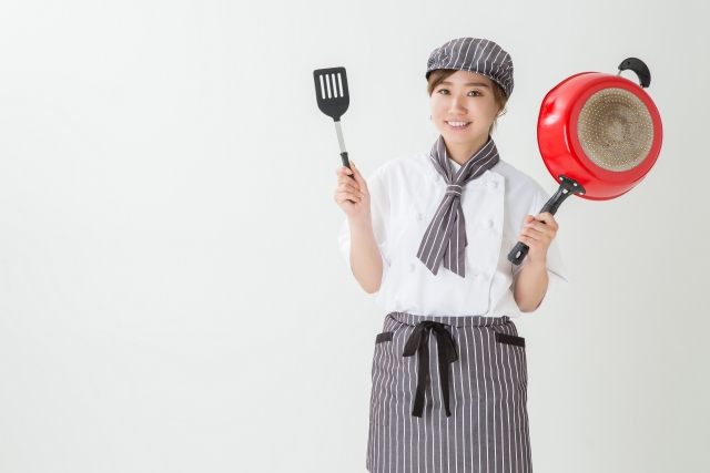 フライと鍋を両手に持ちこちらに微笑む女性スタッフ