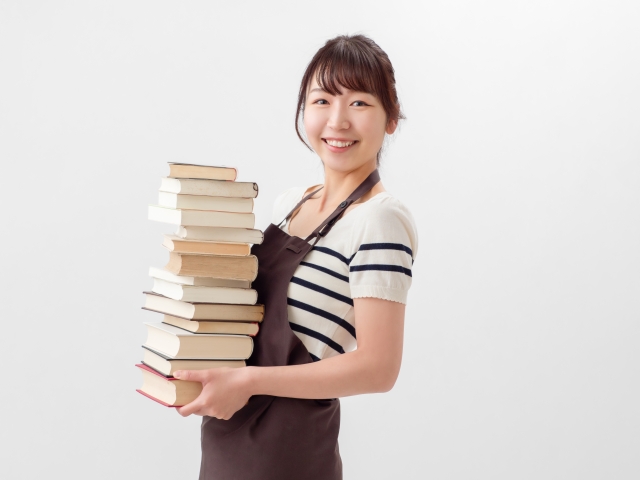 沢山の本を持ちながらこちらに微笑む女性書店員