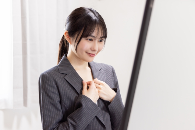 鏡の前で身だしなみを整えるポニーテールの女性