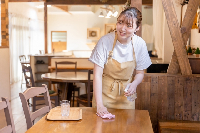 テーブルの下げ膳対応やアルコール消毒をする飲食店スタッフ