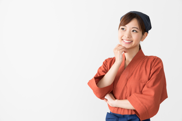 顎に手を当てて考えるそぶりをする和風の制服を着た女性スタッフ
