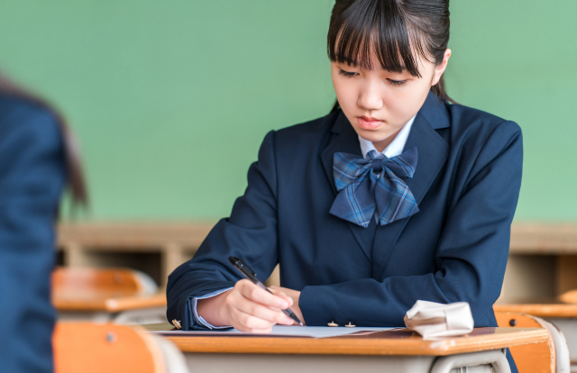 教室で勉強に取り組むブレザー制服の女子学生