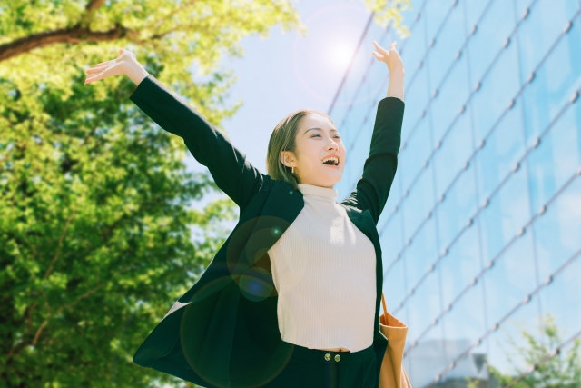 笑顔で伸びをするスーツの女性