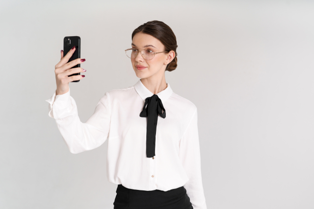 スマホで自撮りするメガネの女性