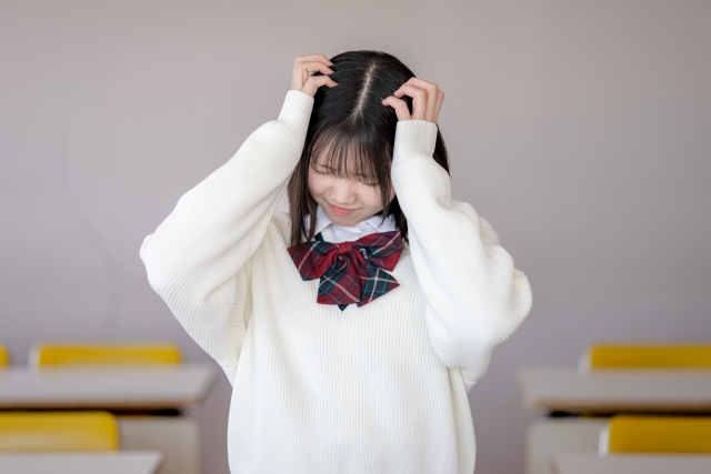 頭を抱える制服を着た女子高生