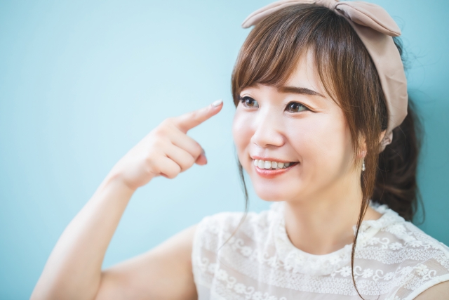 目元を指さす笑顔の女性