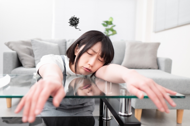 テーブルに突っ伏している若い女性のイメージ
