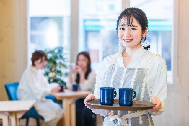 お客様にドリンクを提供する笑顔の女性スタッフ