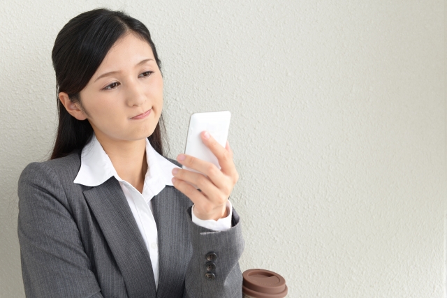 スマホを眺めながら不満そうな女性