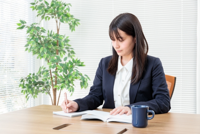 ノートとペンを広げて文字を書き込んでいる女性
