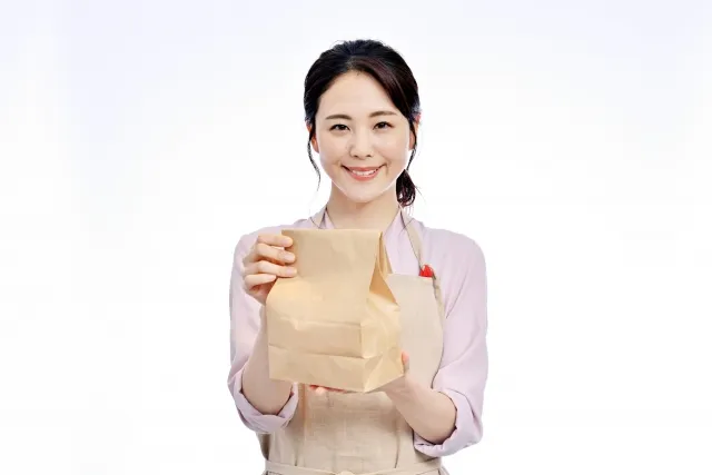 紙袋に入った商品を手渡す女性スタッフ