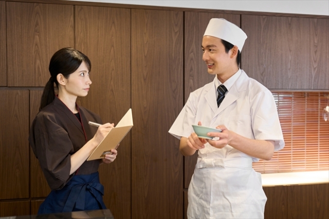 調理スタッフからレクチャーを受ける飲食店の女性スタッフ