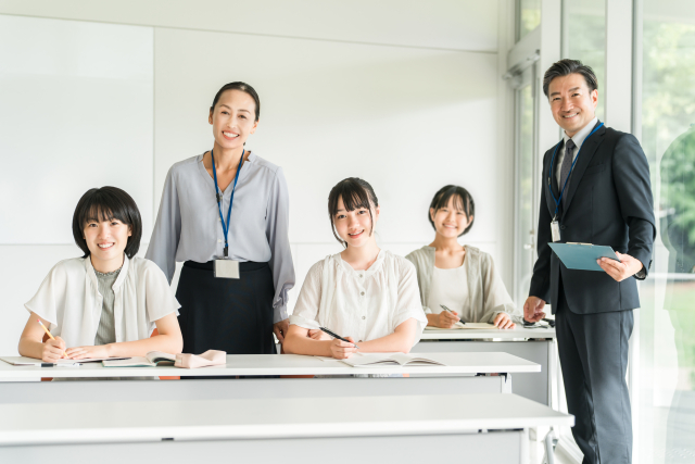 一緒に勉強する3人の女子生徒と男女の講師