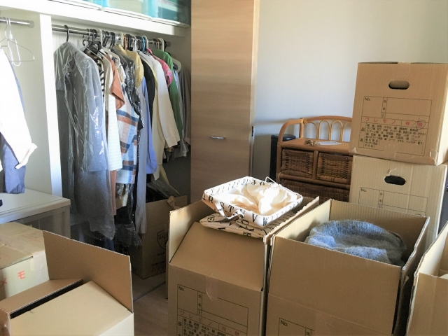 部屋の一角に集められた荷物が入った引っ越し用段ボールのイメージ