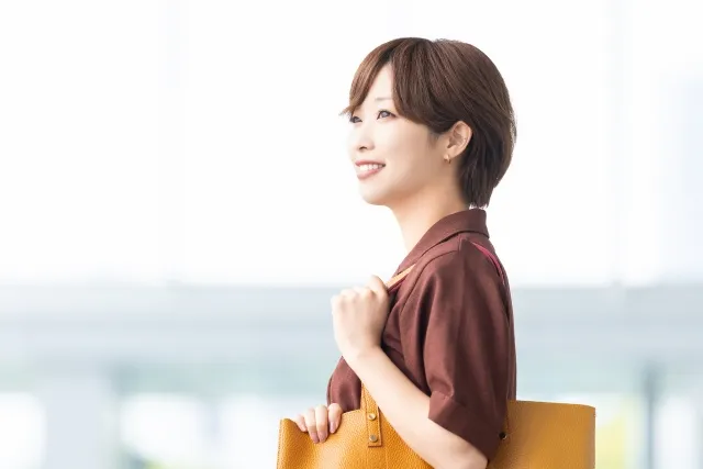 ブラウンの夏用ブラウスを着て出社する笑顔の女性