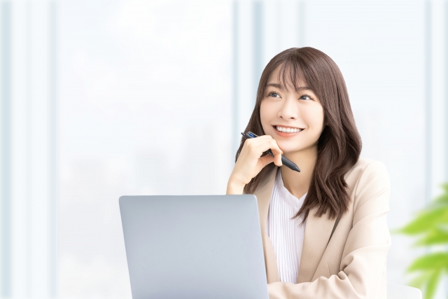 顎に手を当てて思案する笑顔の女性