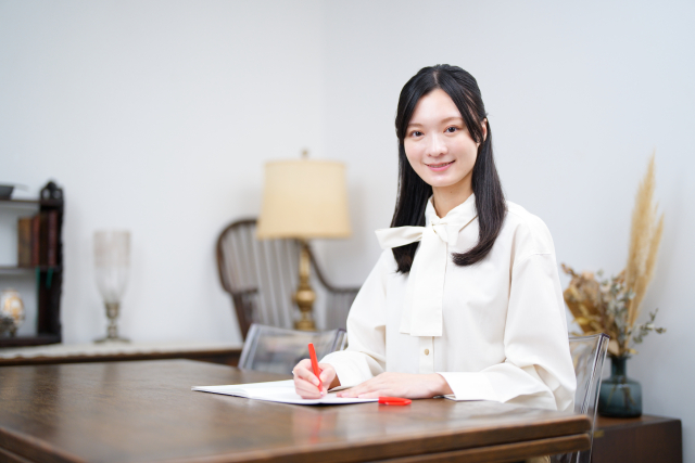微笑みながらテストの添削を行う女性