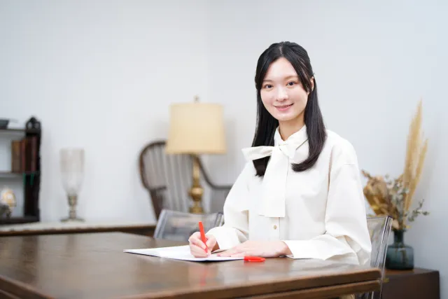 微笑みながらテストの添削を行う女性