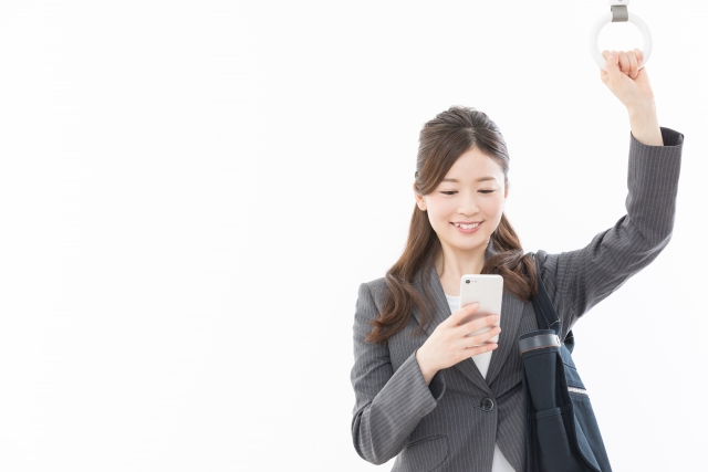 電車で通勤中にスマートフォンを見る女性