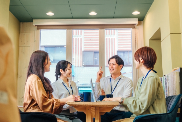 社内カフェスペースで会議する4名の男女スタッフ