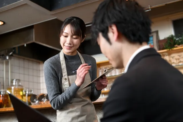 お客様からのご注文をメモに取る女性スタッフ