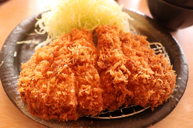 千切りキャベツと一緒に盛り付けられたとんかつのイメージ