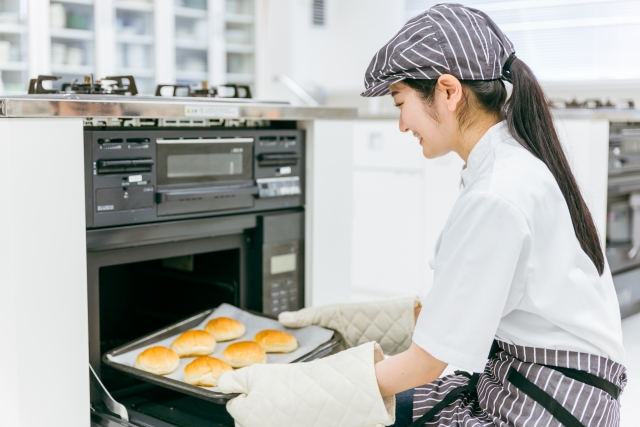 パンをオーブンから取り出す女性店員
