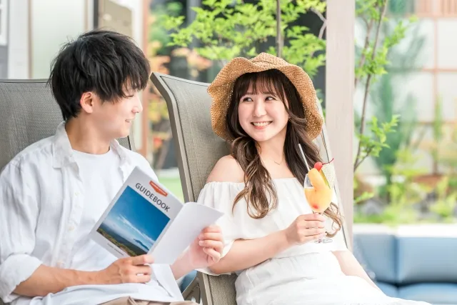 プールサイドのチェアに座って読書やドリンクを楽しむ男女