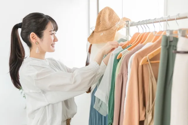 陳列された服を笑顔で整理する女性