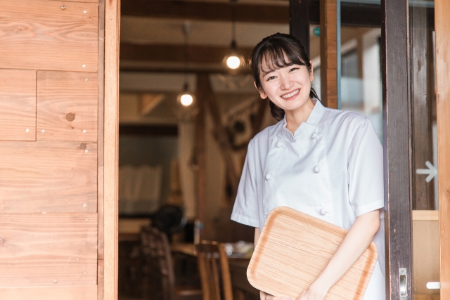 お店の扉の前でお客様を迎え入れる女性店員