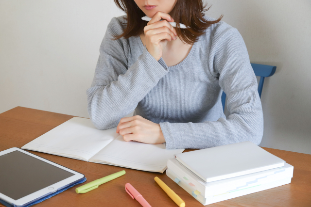 勉強中に考え込む女性とノートや参考書
