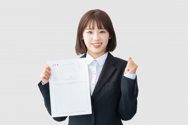 履歴書を持ってガッツポーズをするスーツ姿の女性